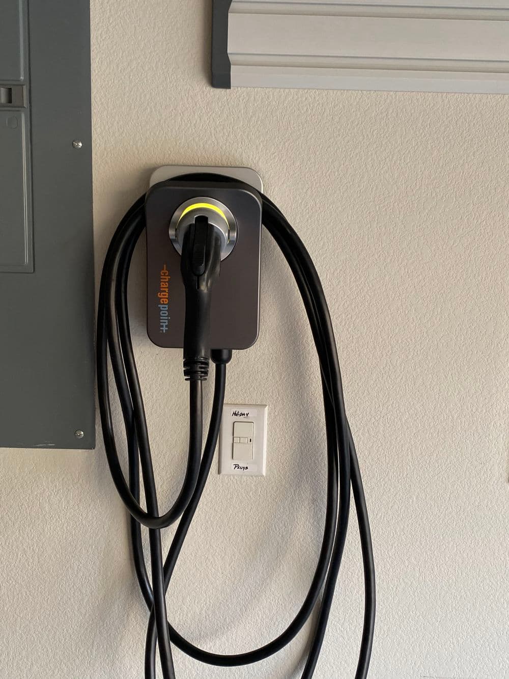 Electric vehicle charging station mounted on a wall with cables neatly arranged.